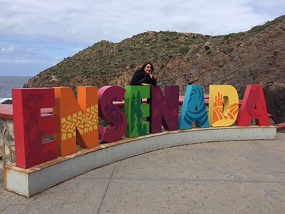 Tourist leaning on Ensenada statue sign at La Bufadora, outside Ensenada, Baja, Mexico